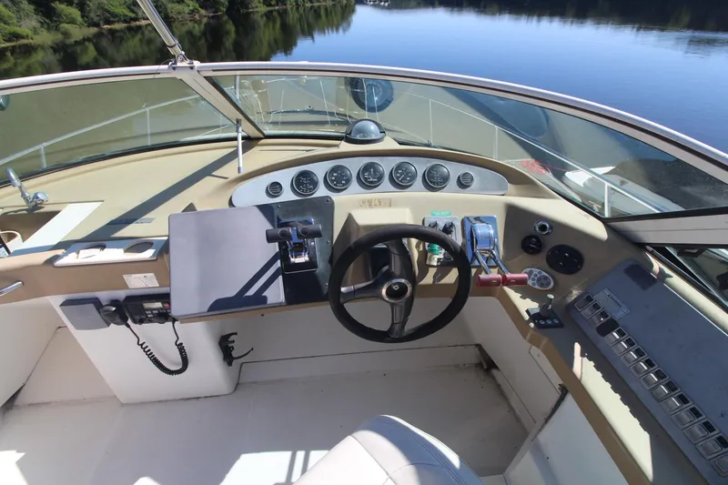 Slide: The Image of 2001 Carver 350 Mariner helm with steering wheel and control panel, overlooking calm water. - 4