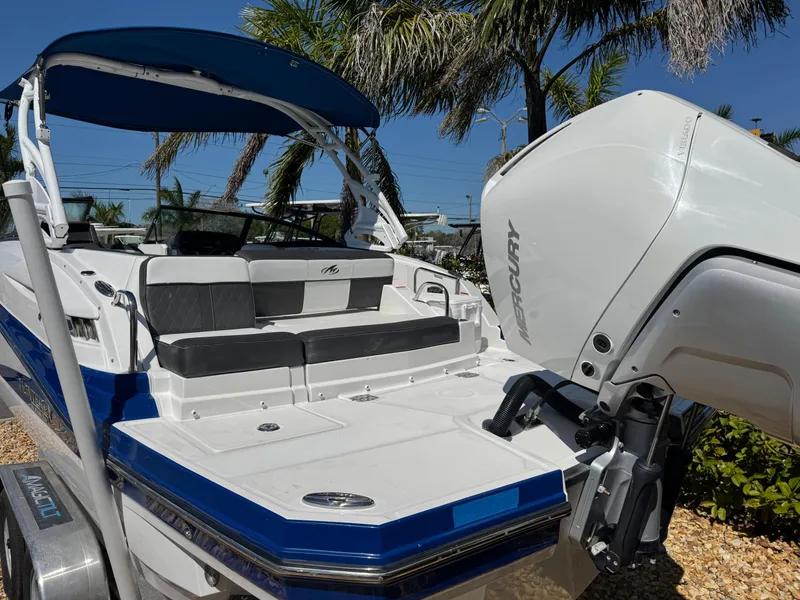 Slide: The Image of 2020 Monterey M-65 boat with Mercury engine, blue and white design, palm trees in background. - 23