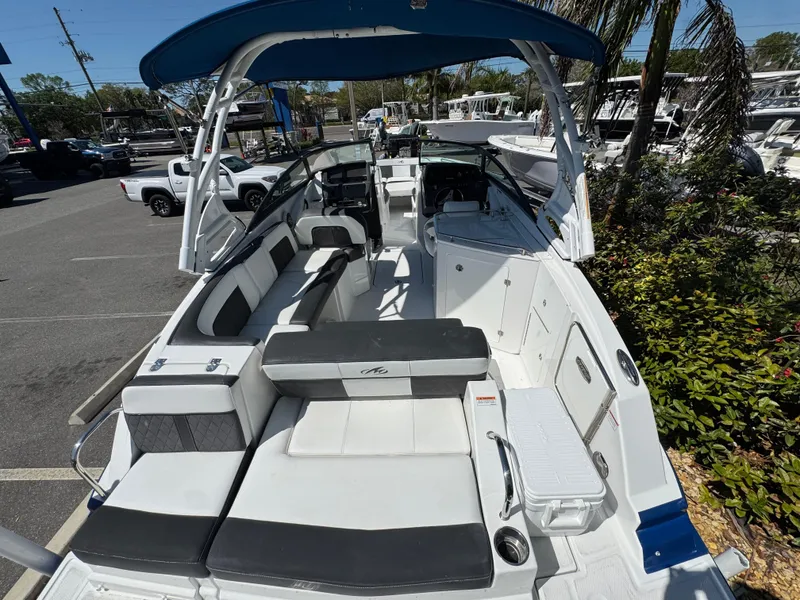 Slide: The Image of 2020 Monterey M-65 boat with spacious seating and blue canopy in a marina setting. - 26