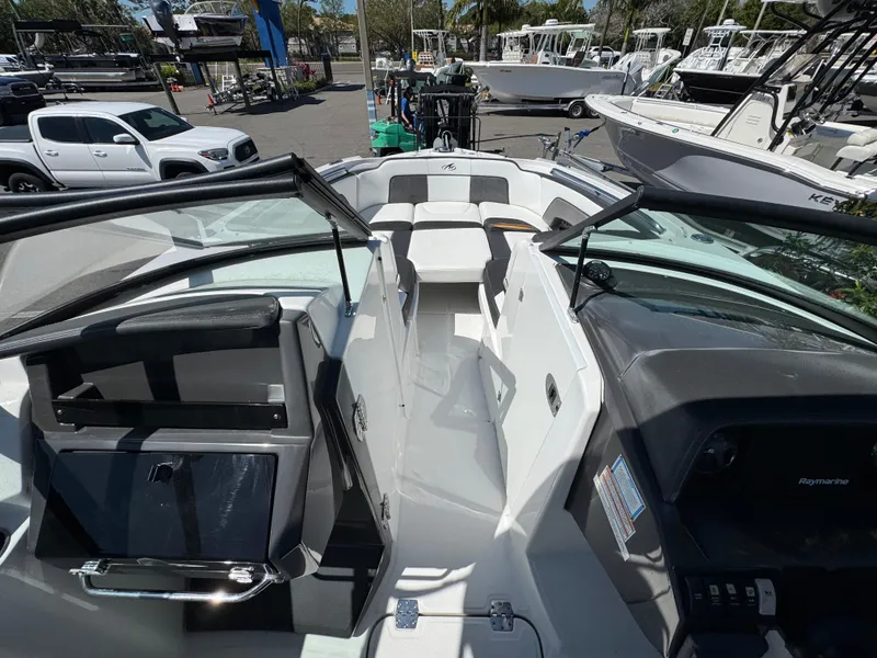 Slide: The Image of 2020 Monterey M-65 boat interior with seating and dashboard, parked among other boats. - 37