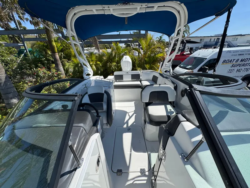 Slide: The Image of 2020 Monterey M-65 boat interior with seating, blue canopy, and lush greenery background. - 42