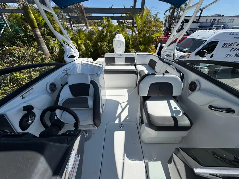 Slide: The Image of 2020 Monterey M-65 boat interior with modern seating and steering wheel, surrounded by lush greenery. - 43
