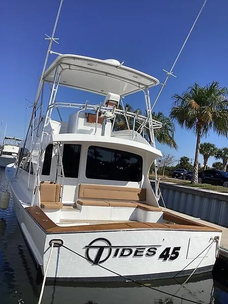 Slide: The Image of 2017 Tides 45 Sportfish boat docked, featuring spacious deck and palm trees in the background. - 1