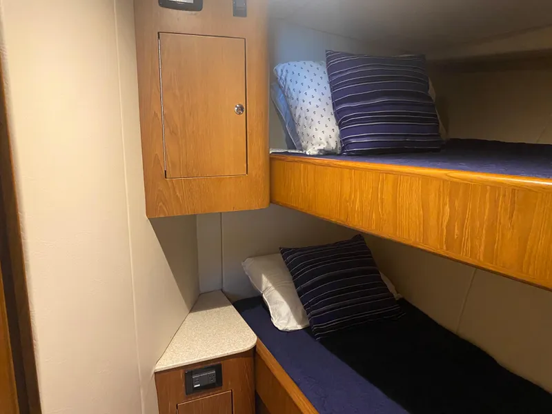 Slide: The Image of Bunk beds in 2017 Tides 45 Sportfish cabin with wooden cabinetry and blue bedding. - 13