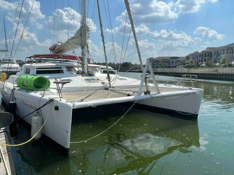The Image of 1995 Voyage Yachts Mayotte catamaran docked in a marina under a partly cloudy sky. - 0