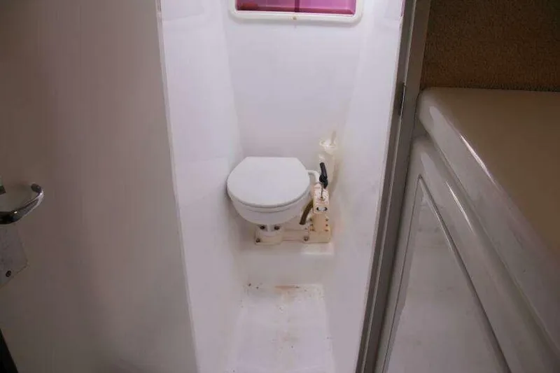 Slide: The Image of Compact bathroom on 1995 Voyage Yachts Mayotte, featuring a marine toilet and white interior. - 22