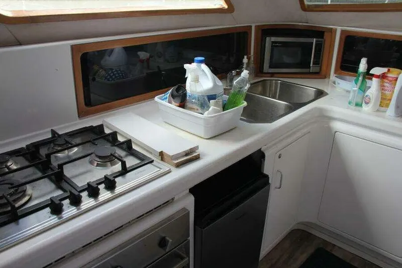 Slide: The Image of 1995 Voyage Yachts Mayotte kitchen with stove, sink, and cleaning supplies. - 29