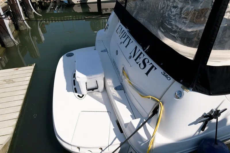 Slide: The Image of 2003 Sea Ray 320 Sundancer docked, rear view with "Empty Nest" name visible. - 10