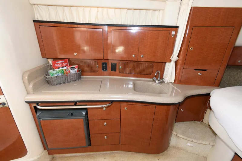 Slide: The Image of 2003 Sea Ray 320 Sundancer cabin kitchen with wooden cabinets and compact sink. - 13