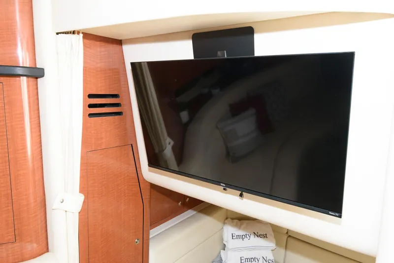 Slide: The Image of 2003 Sea Ray 320 Sundancer interior with mounted flat-screen TV and "Empty Nest" pillows. - 16