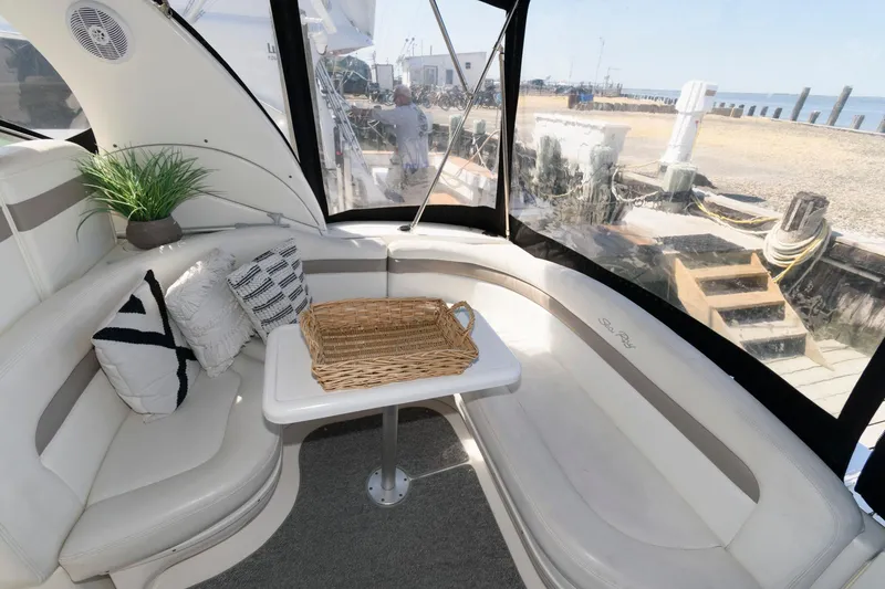 Slide: The Image of 2003 Sea Ray 320 Sundancer interior with cozy seating, decorative pillows, and a wicker basket. - 2