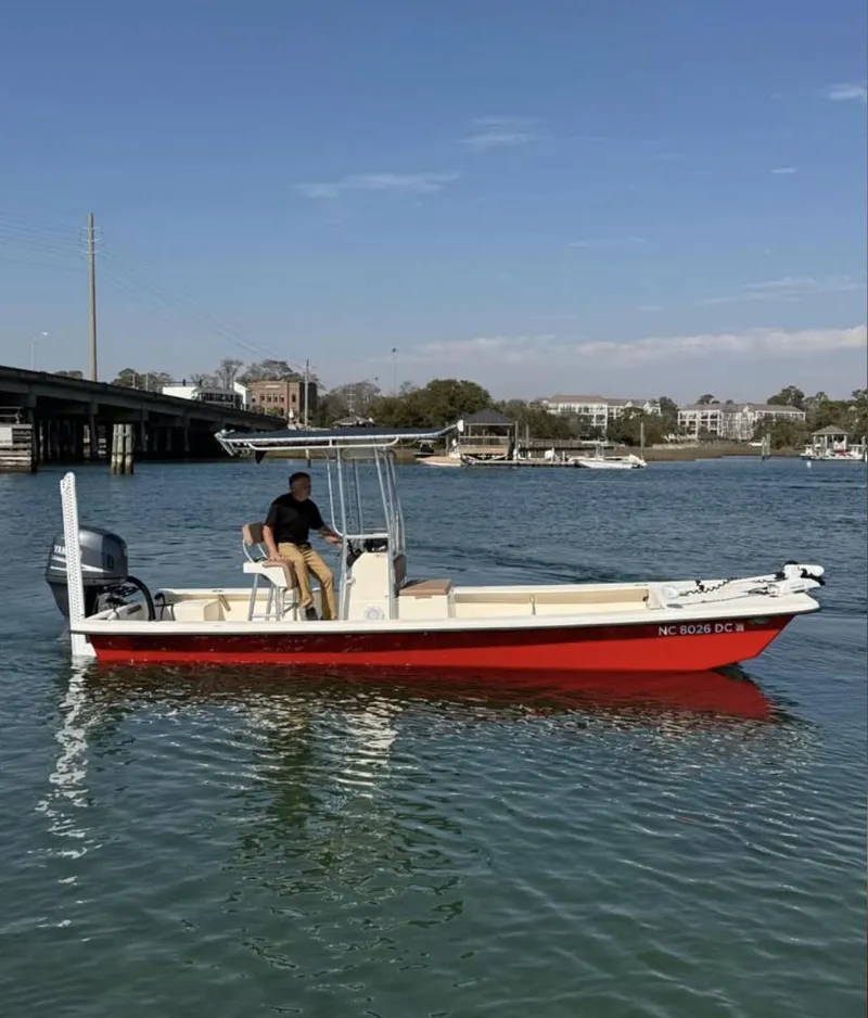 Slide: The Image of 2006 Jones Brothers 23 Bateau boat on water, red hull, under clear sky. - 0