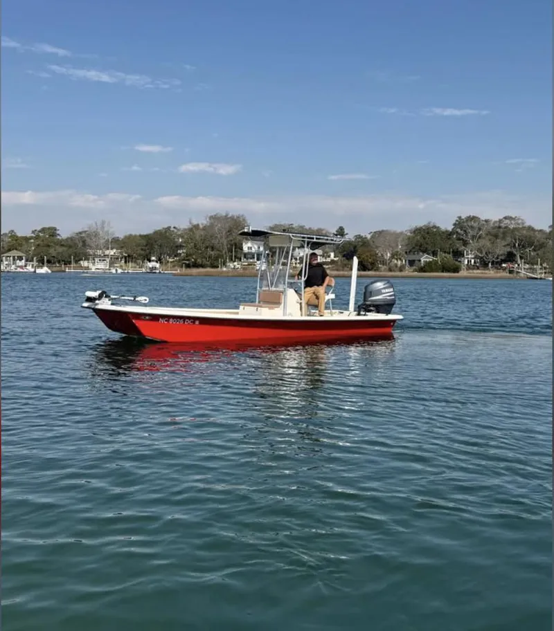 Slide: The Image of 2006 Jones Brothers 23 Bateau boat on calm water, red hull, clear sky background. - 1