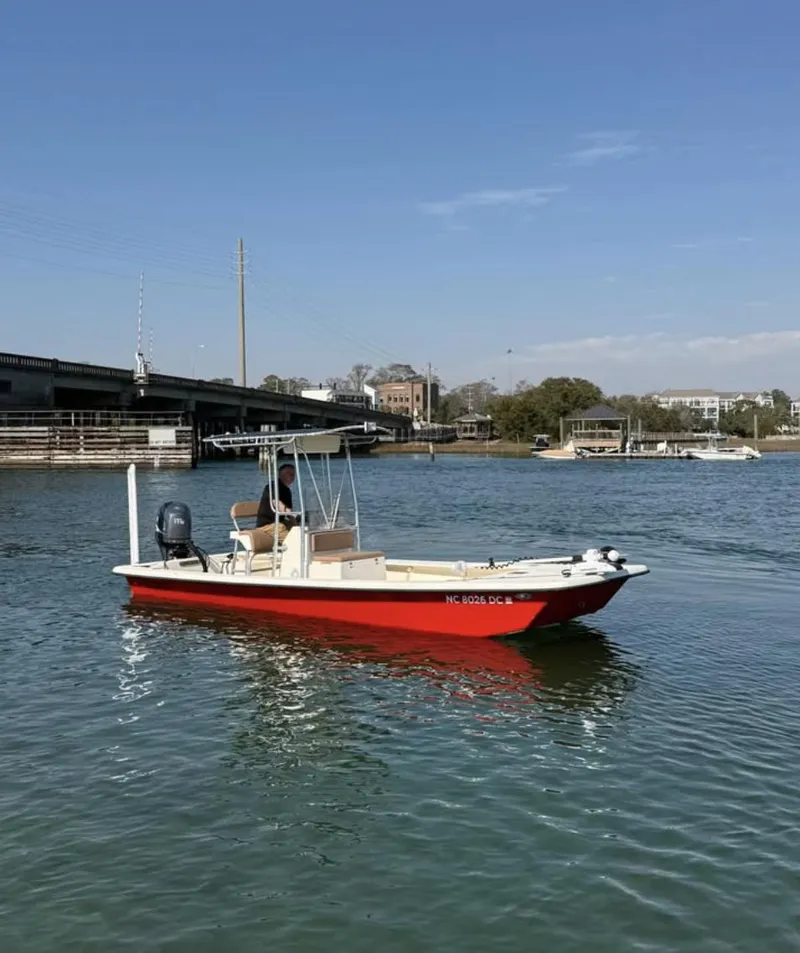 Slide: The Image of 2006 Jones Brothers 23 Bateau boat on calm water near a bridge. - 2
