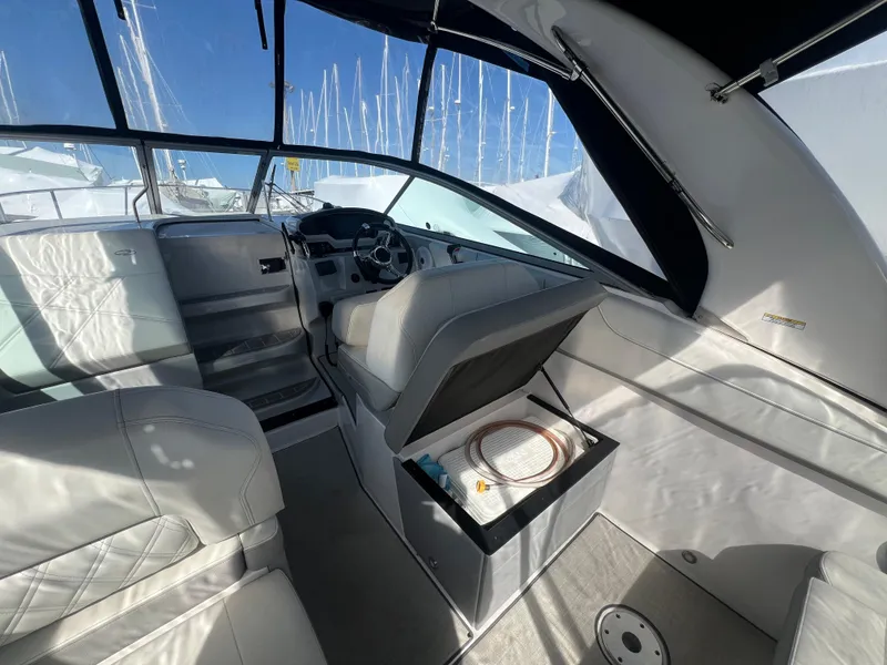 Slide: The Image of 2020 Regal 26 XO boat interior with helm, seating, and storage compartment under sunny skies. - 17