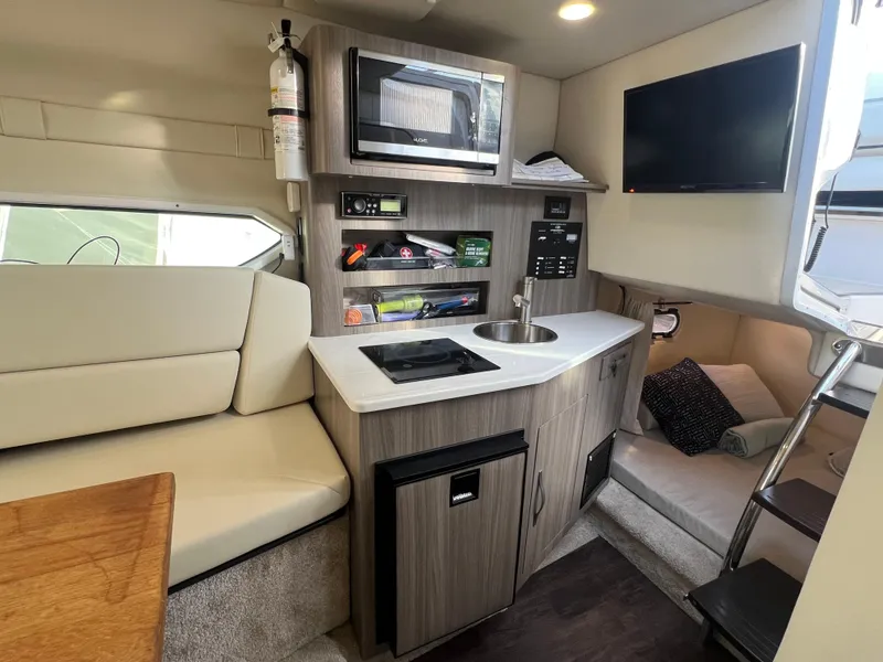 Slide: The Image of 2020 Regal 26 XO boat interior with kitchenette, microwave, seating, and TV. - 28
