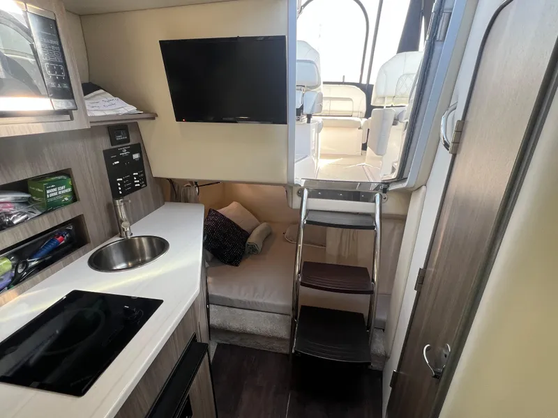Slide: The Image of 2020 Regal 26 XO boat interior with kitchenette, seating, and TV. - 30