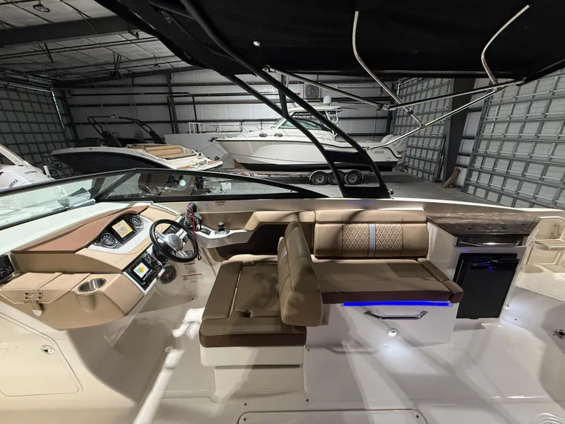 Slide: The Image of 2016 Sea Ray 290 Sundeck Outboard interior with helm, seating, and modern amenities in a garage. - 14