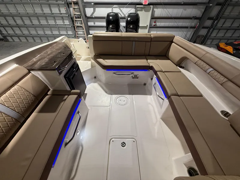 Slide: The Image of 2016 Sea Ray 290 Sundeck Outboard interior with tan seating and blue LED lighting. - 16