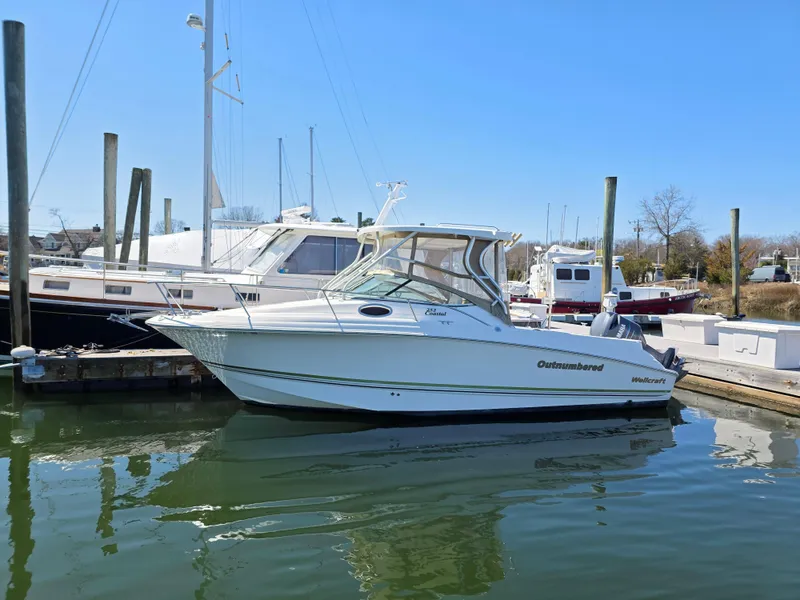 The Image of 2004 Wellcraft 252 Coastal boat docked in a marina under clear blue skies. - 0