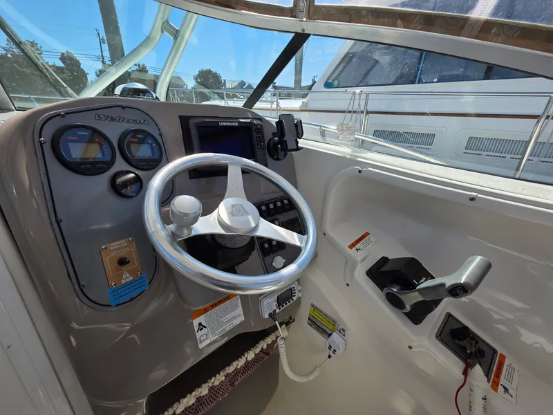 Slide: The Image of 2004 Wellcraft 252 Coastal boat cockpit with steering wheel and control panel. - 3