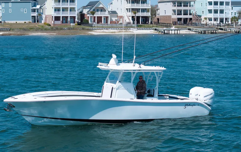 Slide: The Image of 2018 Yellowfin 32 Offshore boat cruising near coastal homes. - 1