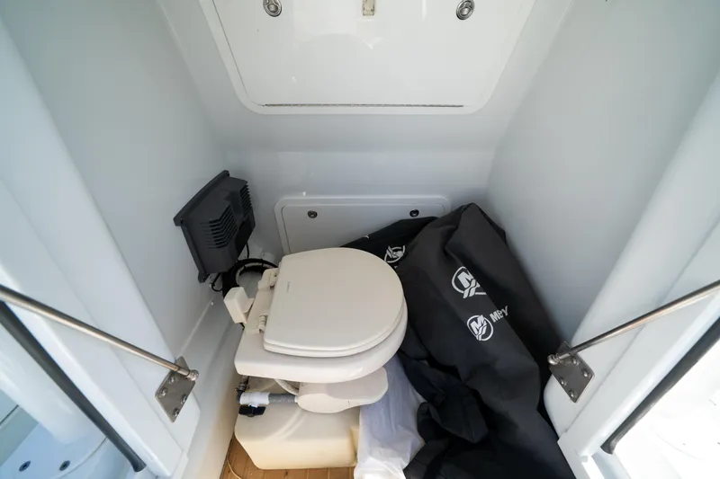 Slide: The Image of 2018 Yellowfin 32 Offshore boat interior with compact marine toilet and storage area. - 12