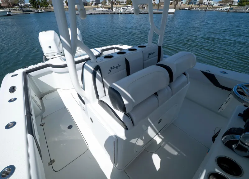 Slide: The Image of 2018 Yellowfin 32 Offshore boat interior with cushioned seating, docked by the water. - 6