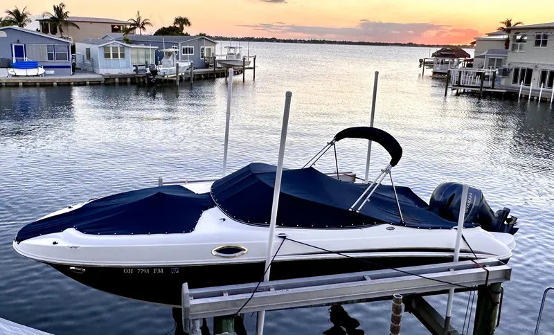 The Image of 2015 Stingray 234 Series boat docked at sunset by waterfront homes. - 0
