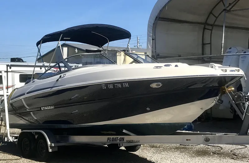 Slide: The Image of 2015 Stingray 234 Series boat on trailer with canopy, parked outdoors. - 3