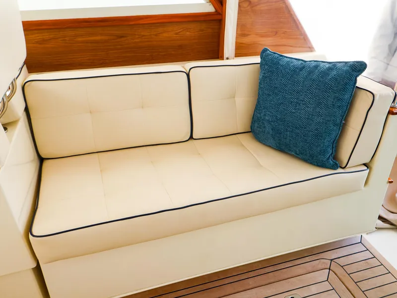 Slide: The Image of Cream sofa with blue cushion on Legacy 32, 2009 model, featuring wooden accents. - 12