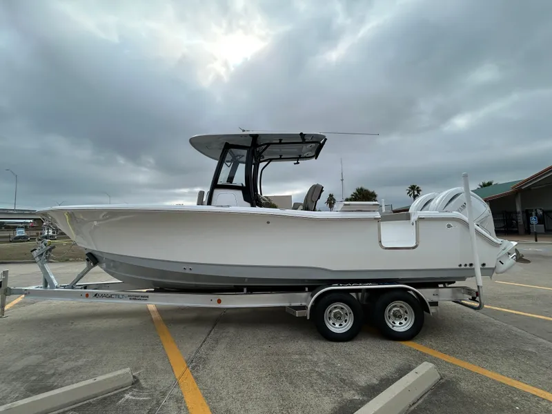 Slide: The Image of 2025 Sea Hunt Gamefish 27 with Coffin Box on trailer, parked outdoors under cloudy sky. - 7