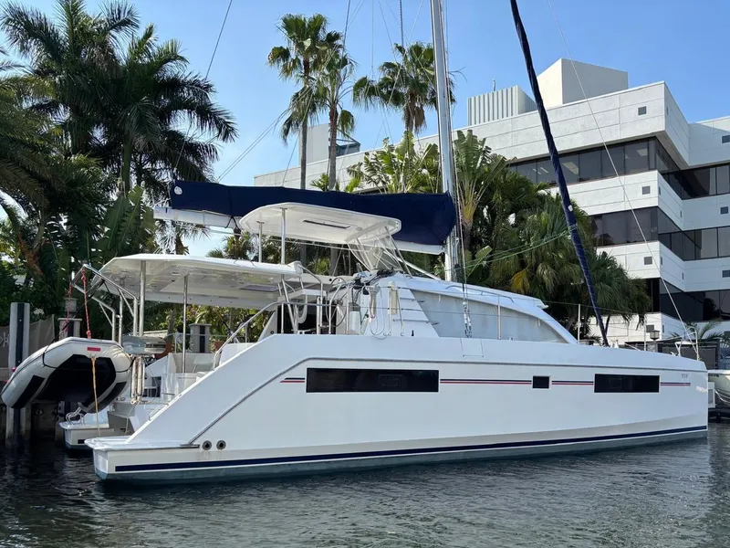 Slide: The Image of 2019 Leopard 40 catamaran docked near palm trees and modern buildings. - 0