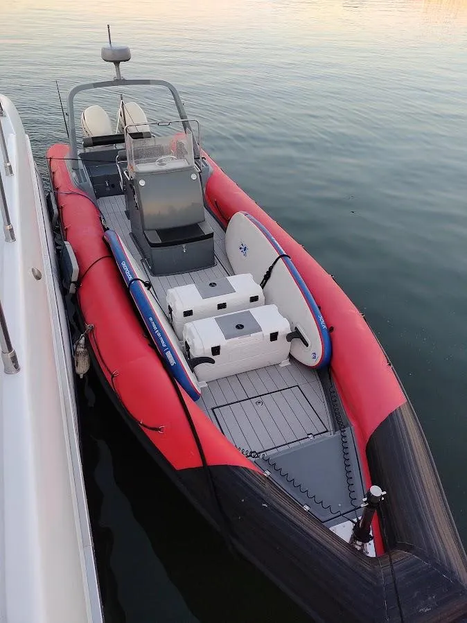 Slide: The Image of Inflatable Rigid boat, 2016 model, docked on calm water with paddleboards. - 10