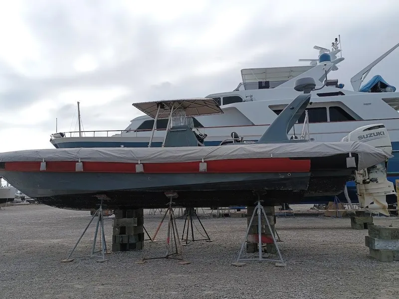 Slide: The Image of Inflatable Rigid boat, 2016 model, on stands beside larger yacht, overcast sky. - 11