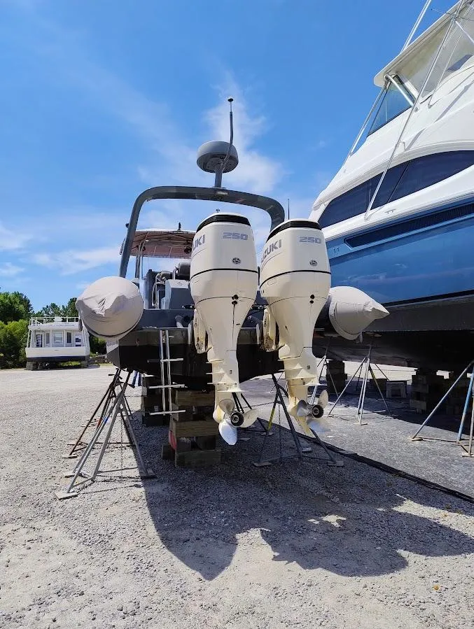 Slide: The Image of Inflatable Rigid boat with dual Suzuki outboard motors, parked on gravel, under clear blue sky. - 12