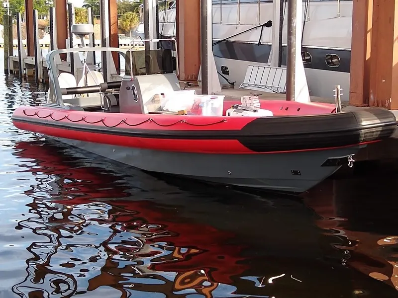 Slide: The Image of Inflatable Rigid boat, 2016 model, docked in marina with red and black design. - 6