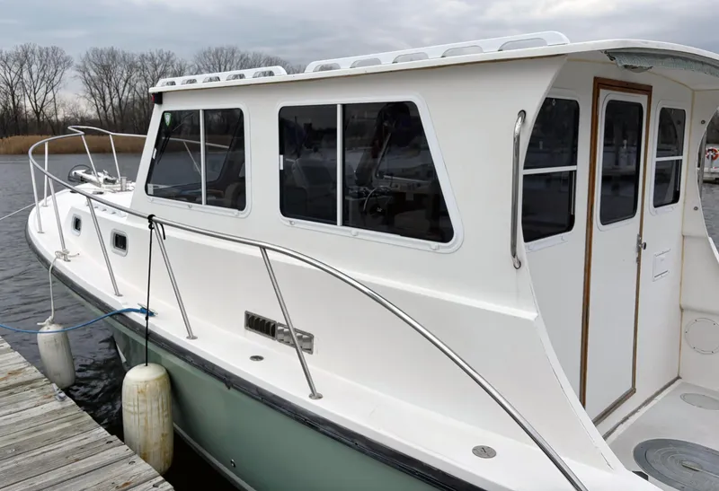 Slide: The Image of 2008 Eastern Casco Bay 31 boat docked, featuring a white cabin and sleek design. - 4