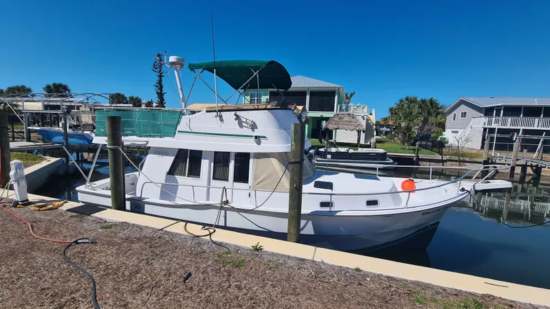 Slide: The Image of 1999 Mainship 350 Trawler docked in a sunny marina setting. - 0