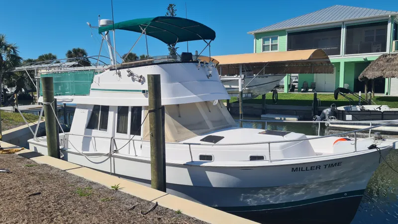 Slide: The Image of 1999 Mainship 350 Trawler docked, featuring green canopy and white exterior. - 1