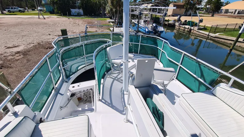 Slide: The Image of 1999 Mainship 350 Trawler with green rail covers, docked near a canal. - 13