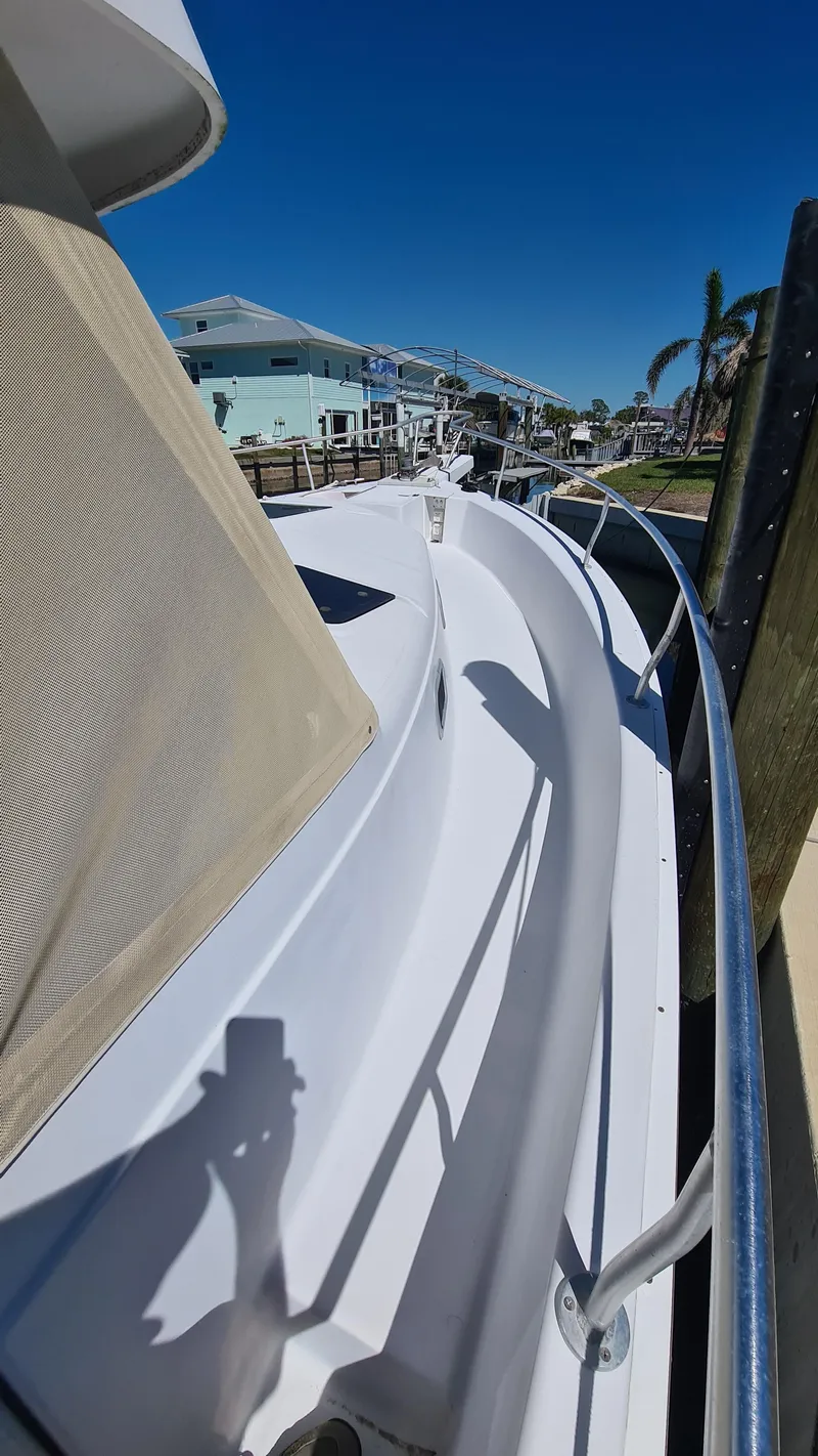 Slide: The Image of 1999 Mainship 350 Trawler docked, showcasing sleek white deck and railing under clear blue sky. - 15