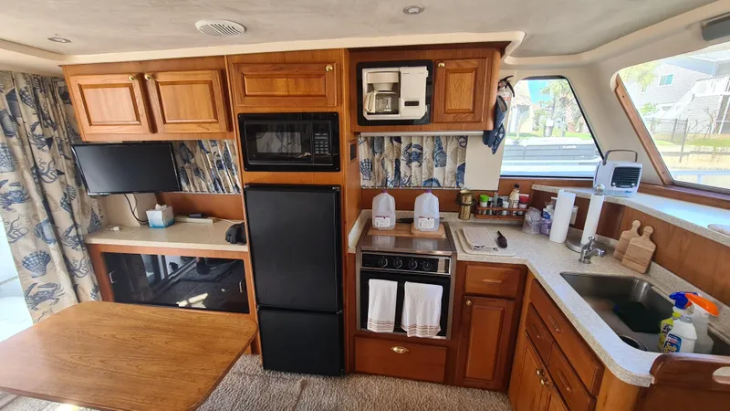 Slide: The Image of Interior of a 1999 Mainship 350 Trawler with kitchen amenities and wooden cabinetry. - 19