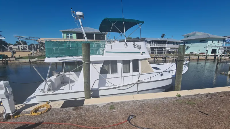 Slide: The Image of 1999 Mainship 350 Trawler docked in a marina under clear blue skies. - 2