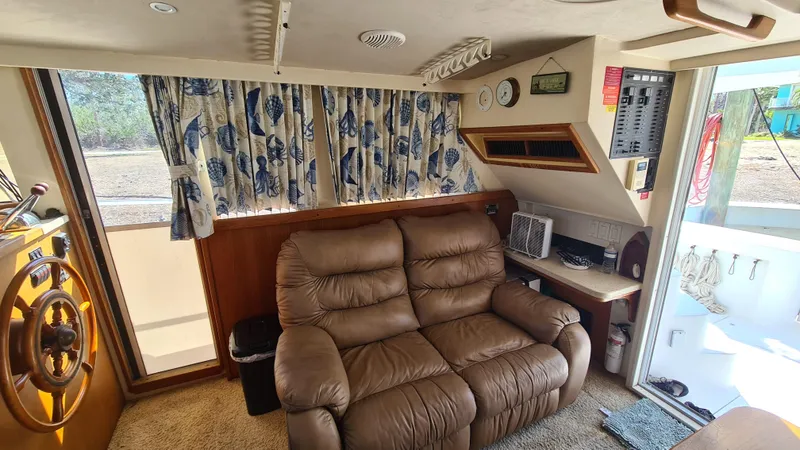 Slide: The Image of 1999 Mainship 350 Trawler interior with brown leather sofa, nautical decor, and helm station. - 20