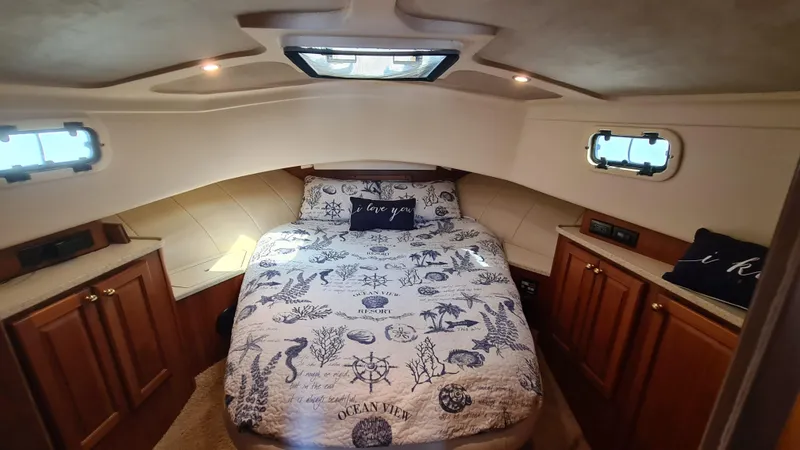 Slide: The Image of Cozy bedroom in 1999 Mainship 350 Trawler with nautical-themed bedding and wooden cabinets. - 23