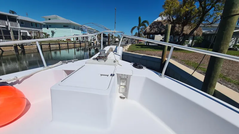 Slide: The Image of 1999 Mainship 350 Trawler docked, showcasing deck and railing under clear blue sky. - 5