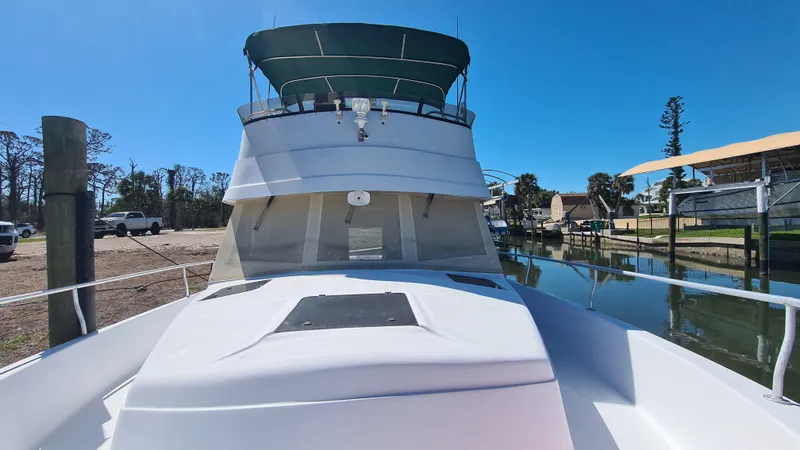 Slide: The Image of 1999 Mainship 350 Trawler docked, featuring a spacious deck and green canopy. - 6