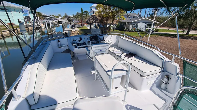 Slide: The Image of 1999 Mainship 350 Trawler with spacious deck and seating, docked in a scenic marina. - 8