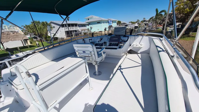 Slide: The Image of 1999 Mainship 350 Trawler boat deck with seating and helm, under sunny skies. - 9